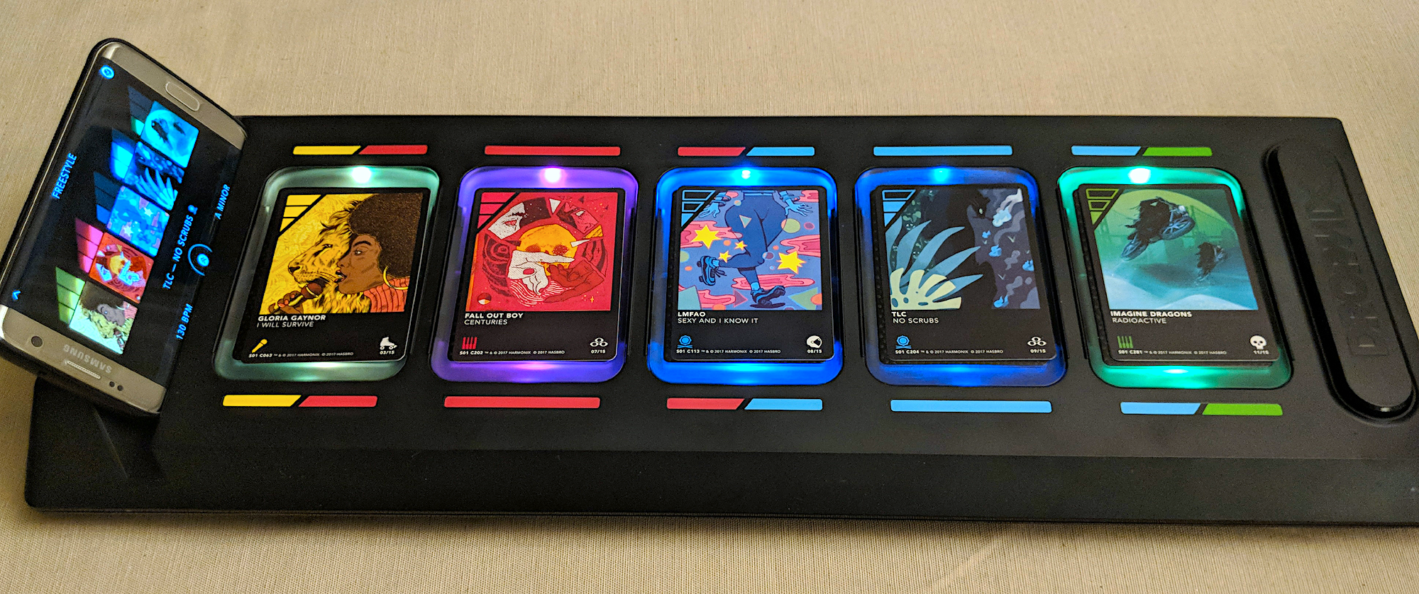 DropMix physical board with smartphone and five colorful music cards showing various artists